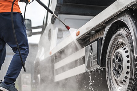 A man pressure washing a truck outdoors; Adobe Stock: 362537107
