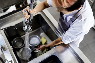 Top view of kitchen staff washing utensils at sink; Adobe Stock: 178066106