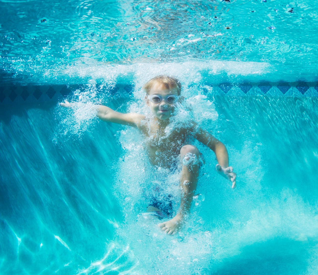 Young boy playing underwater with bubbles and goggles